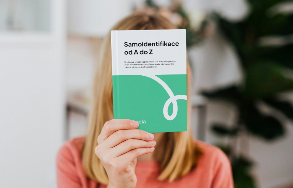 a woman holding a book in front of her face, partially obscuring her features.